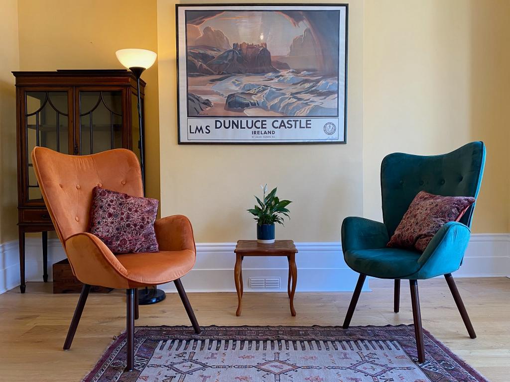 Becky's therapy room: two armchairs, one burnt orange and one deep teal, facing each other with a small table and plant between them